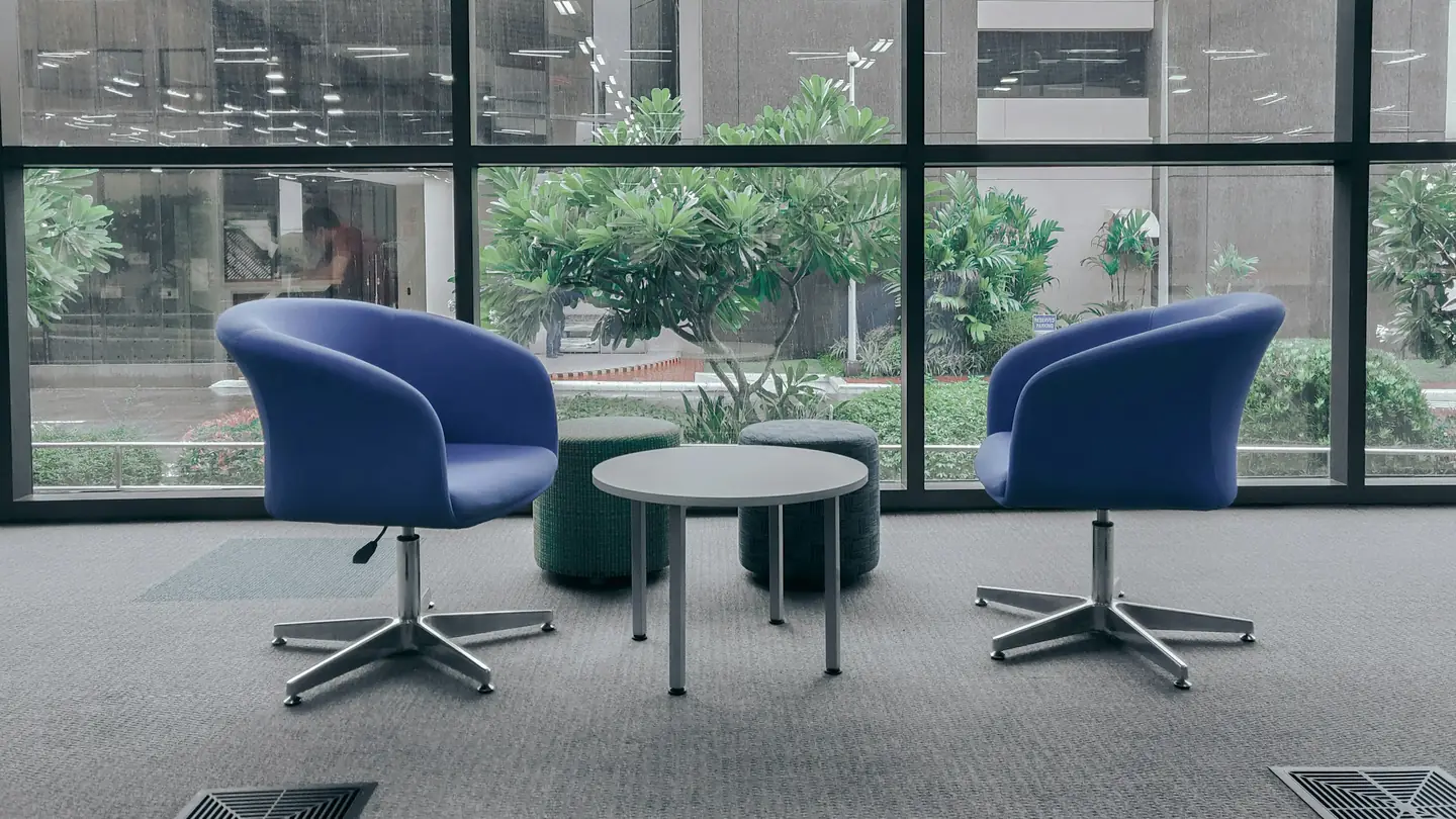 Two armchairs facing each other across a small table beside a window.